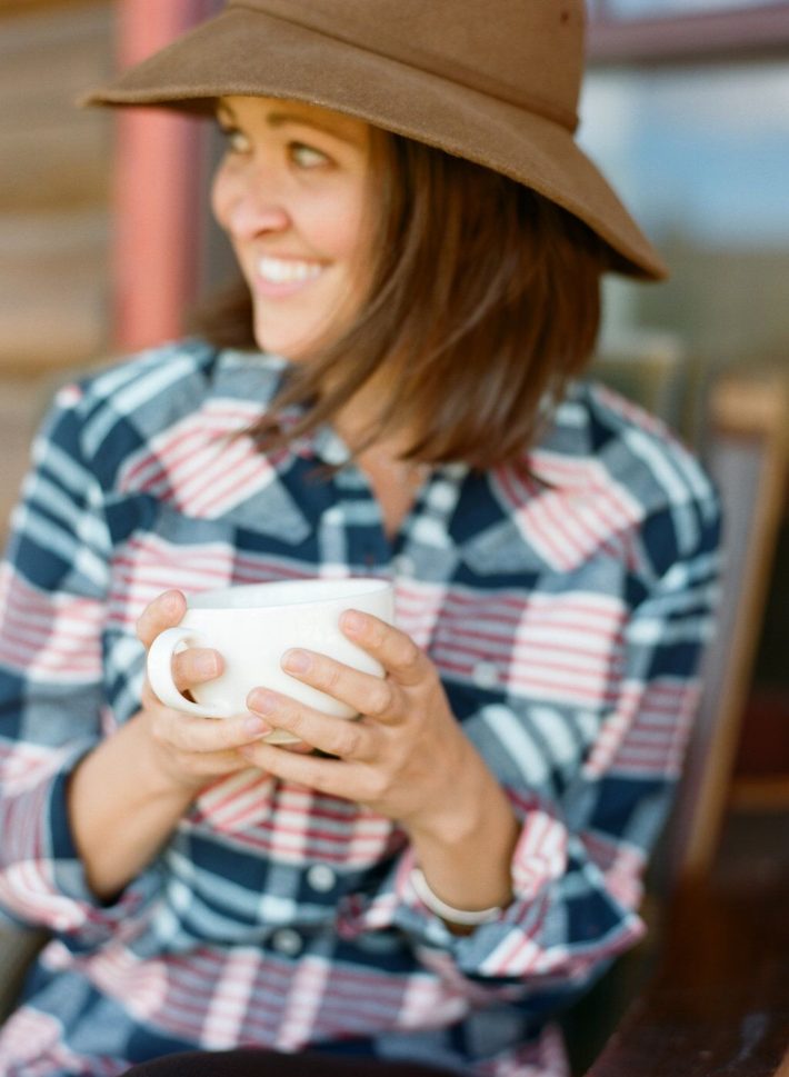 Mountain Town Blogger Meagan Murtagh enjoys coffee in a Stio flannel at Turpin Meadow Ranch in Jackson Hole Wyoming