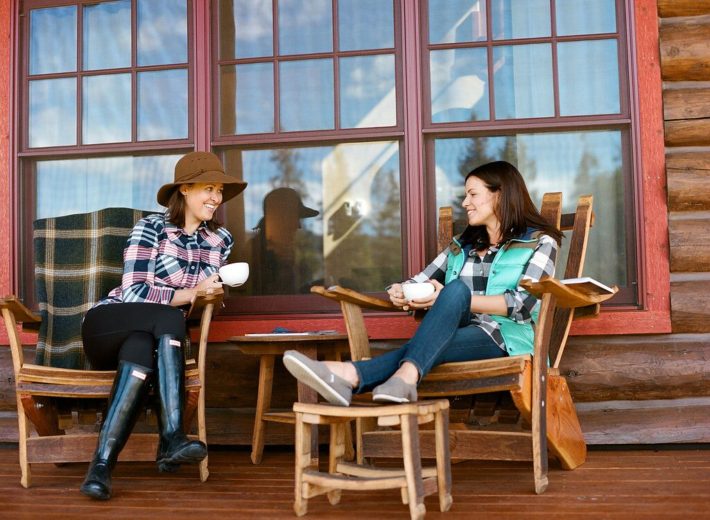 Jackson Hole Blogger Meagan and friend sit on the porch of Turpin Meadow Ranch sipping coffee 