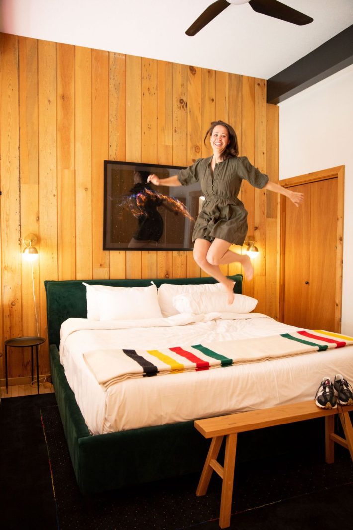 Girl jumping on bed at Sideral Haus in Jackson Hole with pendleton blanket