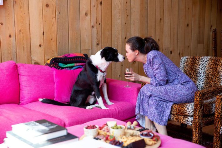 dog kissing girl on pink couch