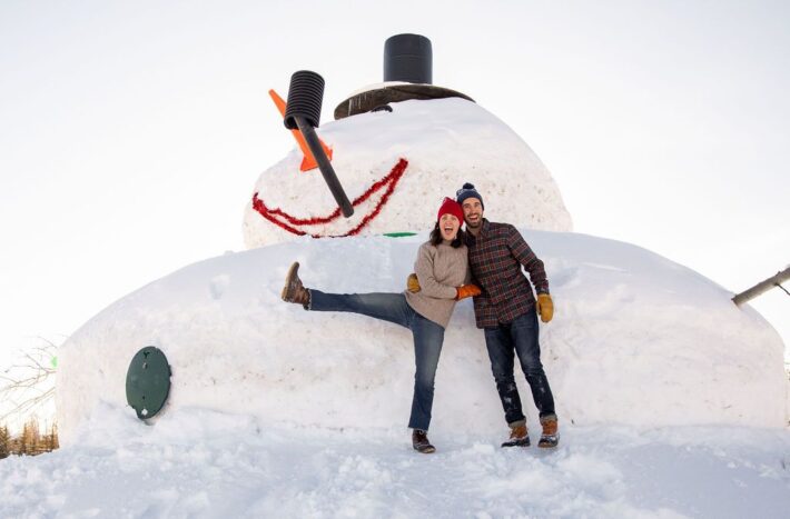 couple in front of large snowman jackson hole